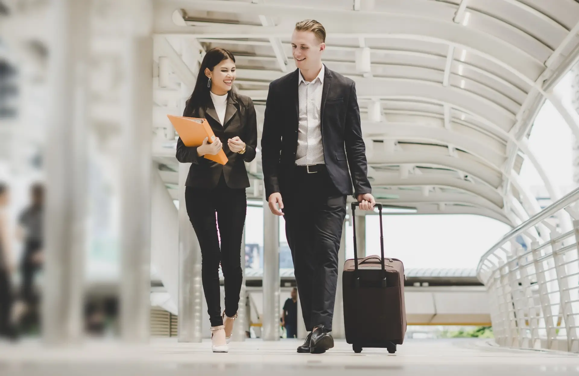 Geschäftsfrau mit Geschäftsmann am Flughafen im Gespräch.