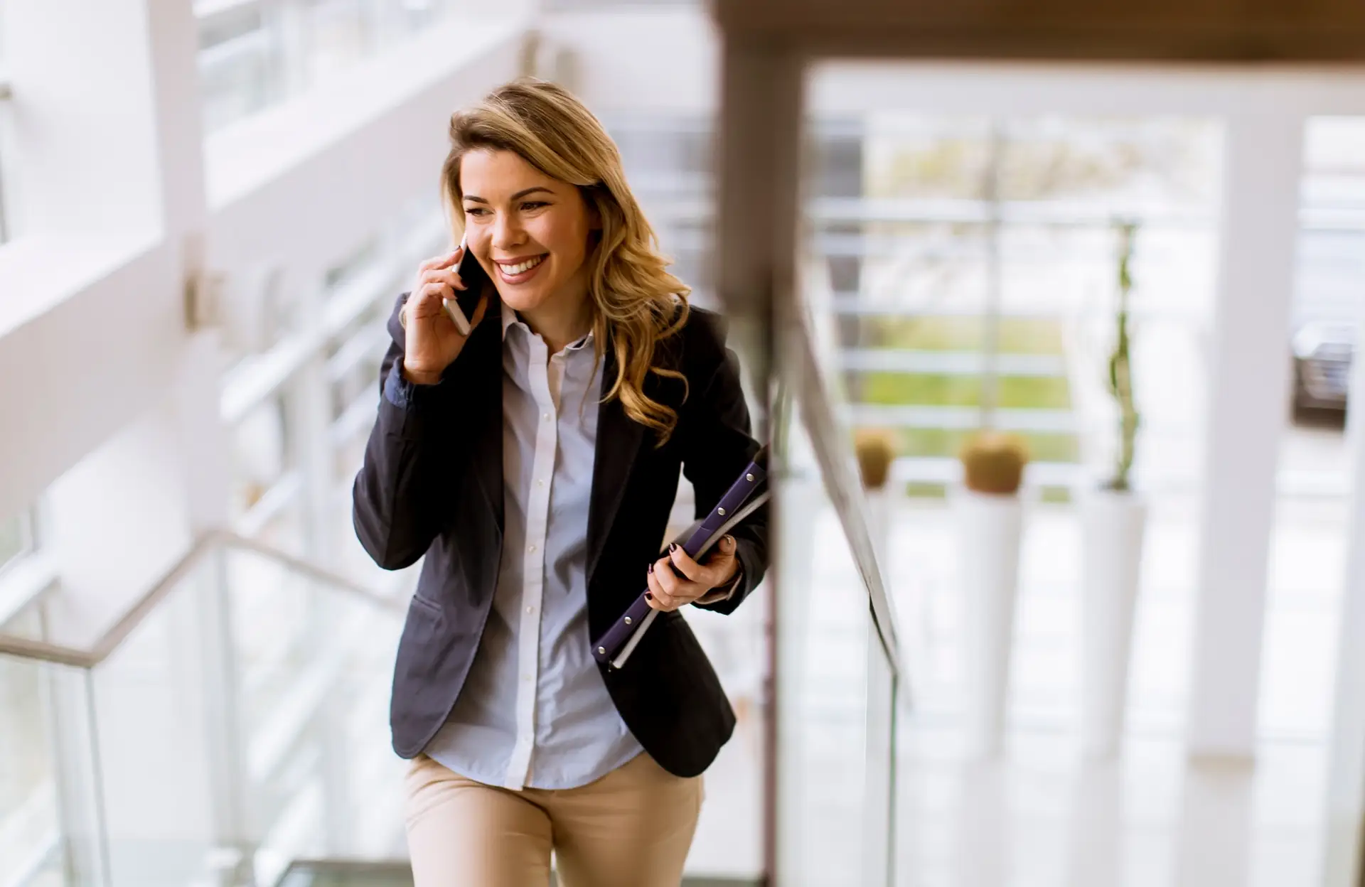 Junge, sympathische Geschäftsfrau mit Handy am Ohr