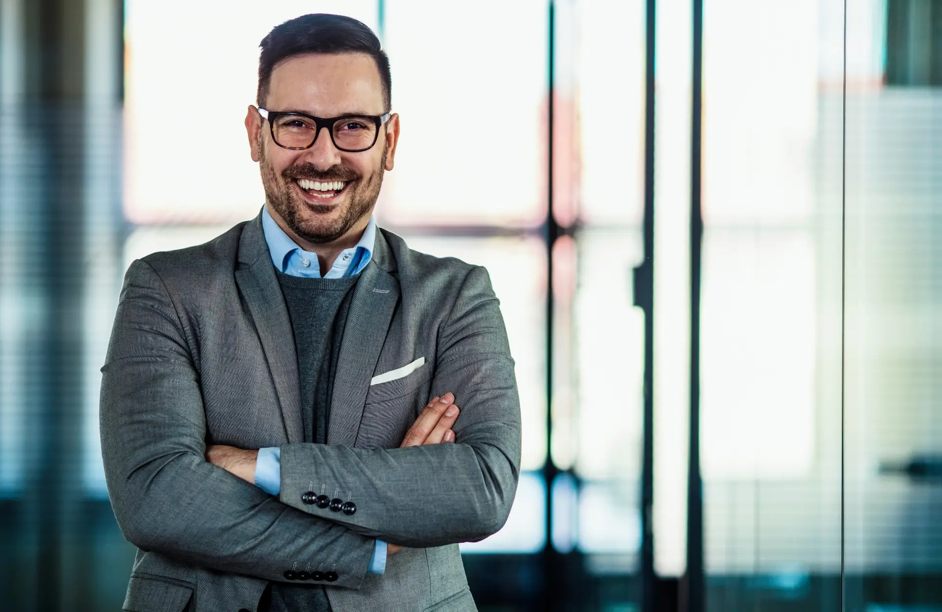 lachender Geschäftsmann in grauem Anzug verspricht eine gute Beratung.