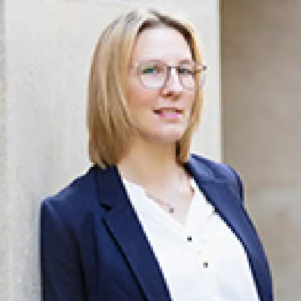 Steuerfachangestellte Anna Fitzau in blauem Blazer und weißem Shirt vor heller Hauswand.