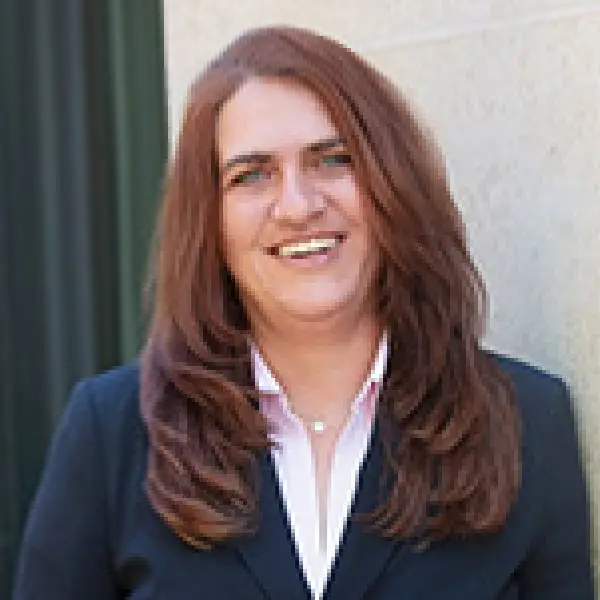 Steuerfachangestellte Claudia Bsdenga in blauem Blazer und heller Bluse vor heller Hauswand.